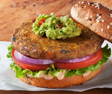 Veggie burger with guacamole, tomato, red onion and lettuce